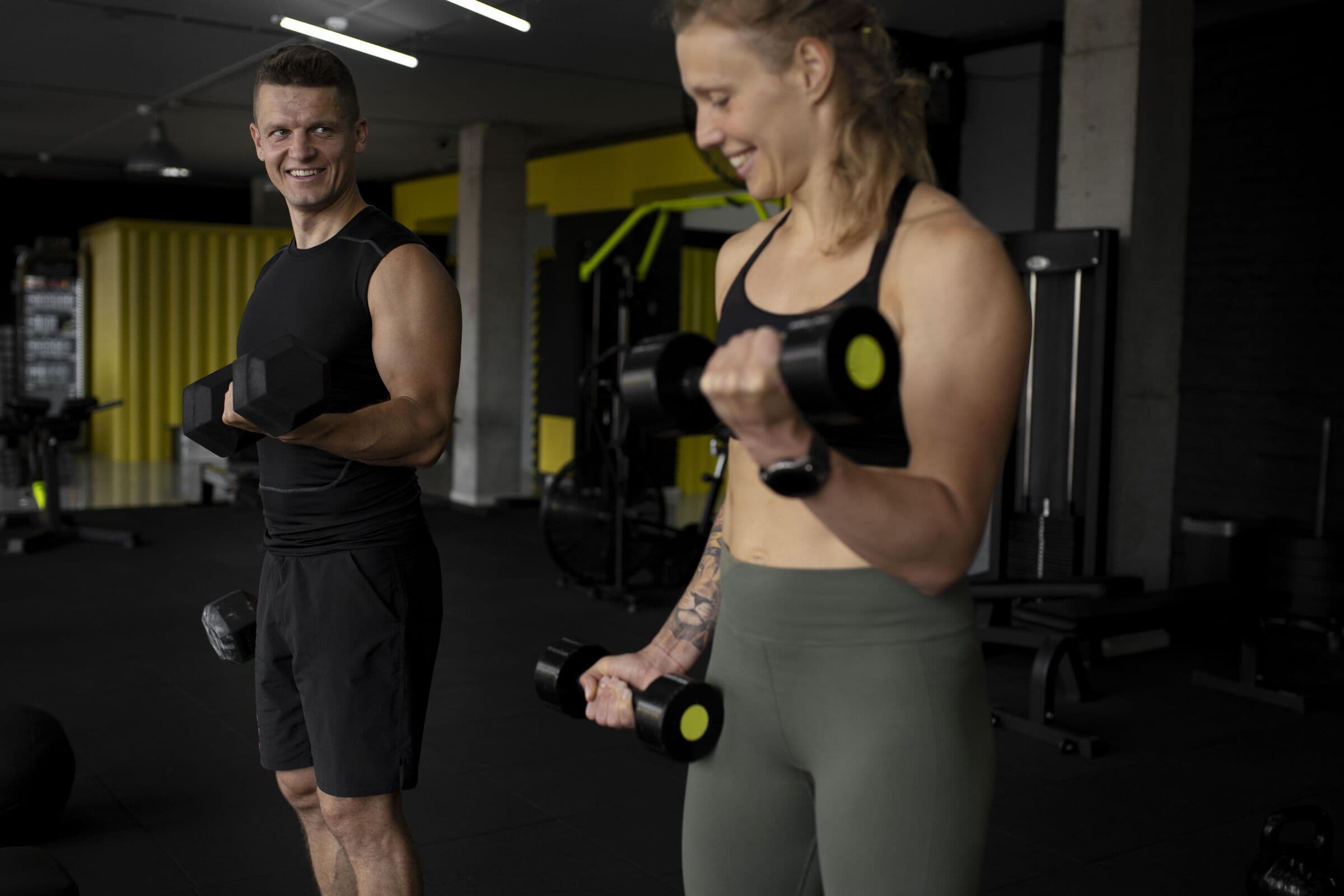 Entrenador y clienta haciendo curl de bíceps con mancuernas